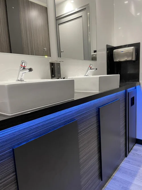Twin vessel sinks with blue LED under-lighting inside luxury trailer